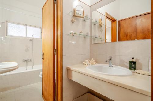 a bathroom with a sink and a mirror and a tub at BeGuest Dream House in Loulé