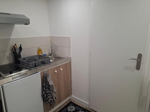 a small kitchen with a sink and a stove at Charmant studio RDC avec terrasse, parking & cuisine équipée in La Côte-Saint-André