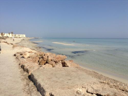 a beach with a retaining wall and the ocean at La Brise de Djerba, Villa de Charme en bord de mer à Al Jazira in Mezraya