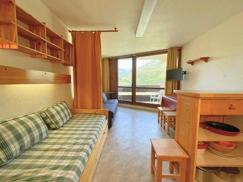 a living room with a couch and a large window at Studio pour 3 avec balcon sud, au pied des pistes, Les Belleville - FR-1-452-191 in Les Menuires