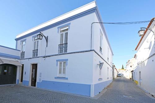 a white building with a large window on a street at Matriz Home in Portel