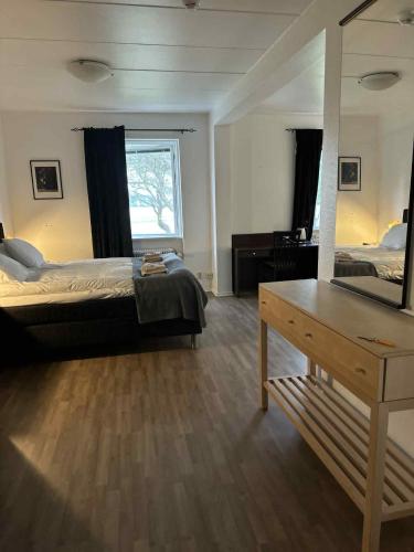a bedroom with a bed and a dresser and a mirror at Burning Bridge Motell & Vandrarhem in Götene