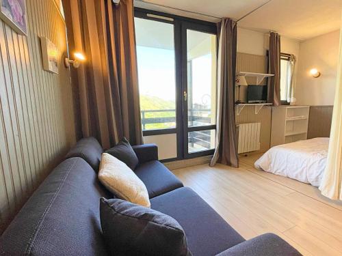 a living room with a blue couch and a bed at Studio avec coin chambre, balcon, cuisine équipée, pied des pistes - Les Ménuires - FR-1-452-262 in Les Menuires