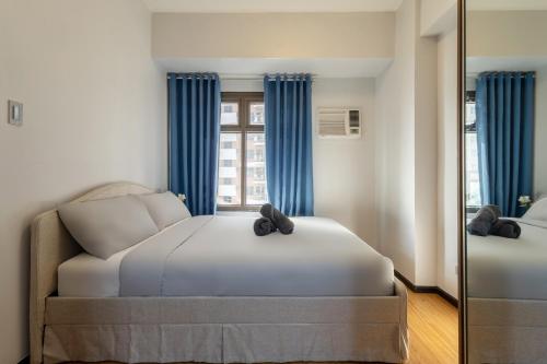a bedroom with a bed with blue curtains and a mirror at The Radiance Manila Bay in Manila