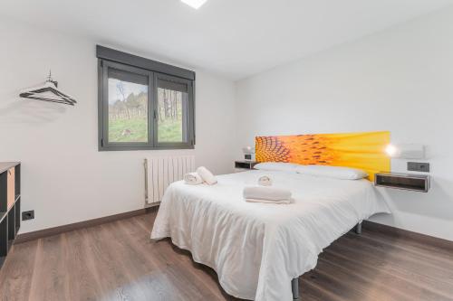 a white bedroom with a large bed with towels on it at Apartamentos Cubicos in Bronchales