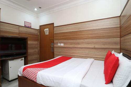 a bedroom with a bed with red pillows and a television at HOTEL O Vivek International Hotel in Jalandhar