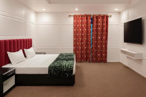 シュリーナガルにあるKoh E Noshのベッドと薄型テレビのある寝室