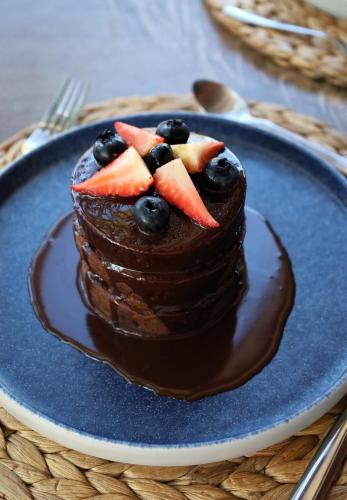 a chocolate cake with fruit on top on a blue plate at Villas Caracol in Holbox Island