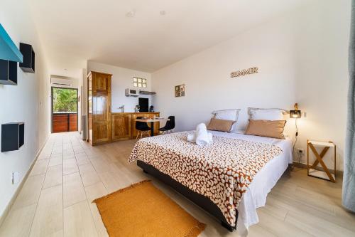 a bedroom with a large bed and a kitchen at Studio Ô Calm - Confort & sérénité, proche aéroport in Saint-Denis