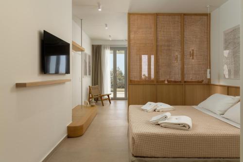 a bedroom with a bed with two white towels on it at KYMA Suites Andros in Gavrion