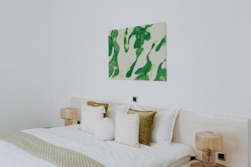 a white bed with white pillows and a painting on the wall at Villa Melograno by Domus Mirus - Rooftop Cinema, Pool, 6-Minute Walk to Beach in Splitska