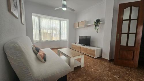 Una sala de estar con un sofá, un televisor y una mesa. en Camaron Beach House By Sanlúcar Housing, en Chipiona