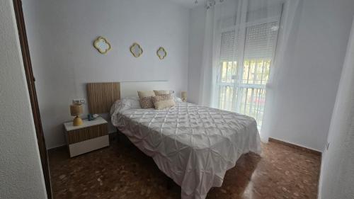 Un dormitorio blanco con una cama y una ventana. en Camaron Beach House By Sanlúcar Housing, en Chipiona