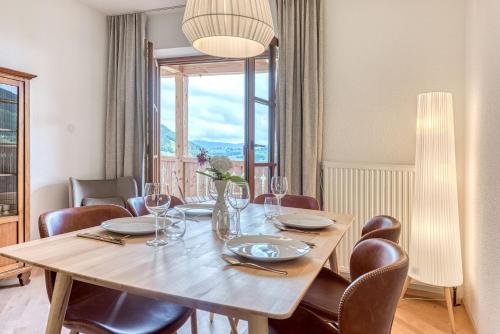 a dining room table with chairs and a large window at ELA Apartments Traunkirchen in Traunkirchen