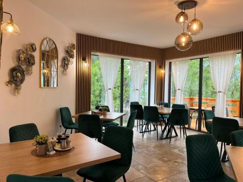 a dining room with tables and chairs and windows at Pensiunea Georgiana in Durau