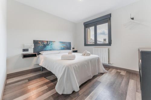 a white bedroom with a bed with two towels on it at Apartamentos Cubicos in Bronchales
