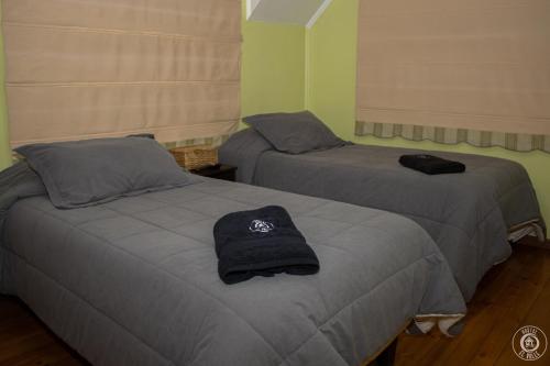 two beds with a hat on them in a room at Hostal el Valle in Angol