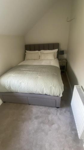 une chambre avec un lit avec un couvre-lit blanc et des oreillers dans l'établissement The Cottage Gortfad, à Garvagh