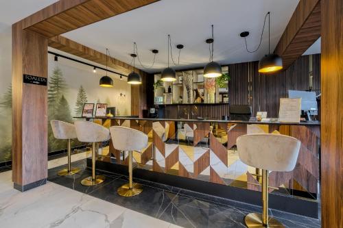 a restaurant with a bar with gold stools at TatryGold - Białka SPA & Resort - Apartament Potoku Szum in Białka Tatrzanska