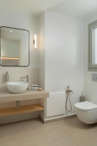 a bathroom with a sink and a toilet and a mirror at KYMA Suites Andros in Gavrion