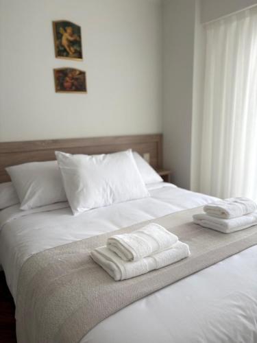 a white bed with two folded towels on it at Cardenal Centro in Monforte de Lemos