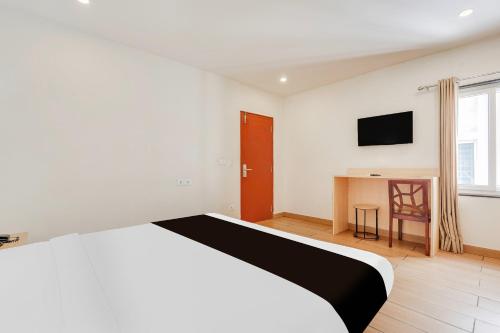 a white bedroom with a bed and a desk at Super Townhouse Visakhapatnam in Visakhapatnam