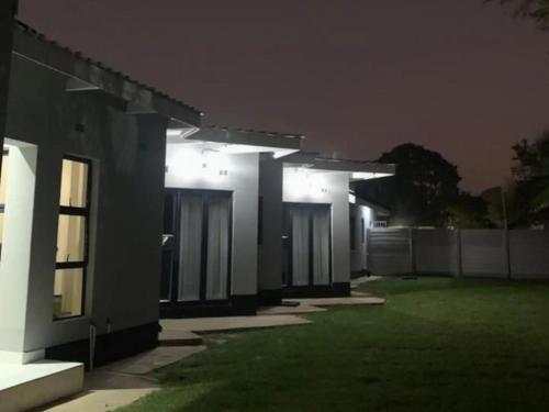 a house lit up at night with lights at Tambarara Manor & Conference Centre in Harare