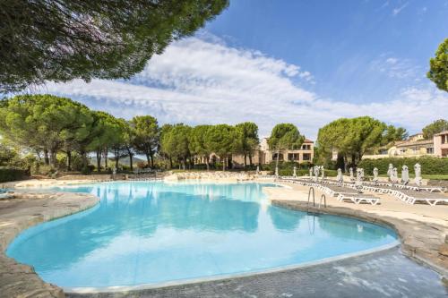 - une piscine dans un complexe avec des chaises et des arbres dans l'établissement Les Coteaux de Pont Royal en Provence - maeva Home - Appartement 3 pièces 6 personnes - Sélection MAE-2554, à Mallemort