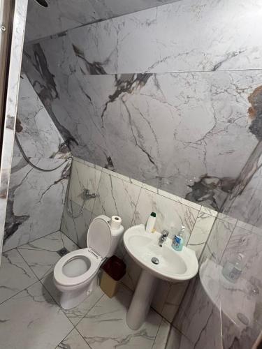 a white bathroom with a toilet and a sink at Guesthouse Driti in Shkodër