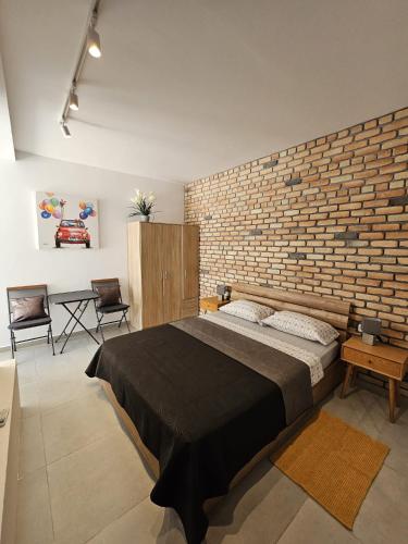 a bedroom with a large bed and a brick wall at Modern Studio near Mgarr harbour in Għajnsielem