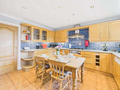 a kitchen with wooden cabinets and a table and chairs at Spacious 3-Bed Home in North Cornwall | Walk to Wadebridge | Near Camel Trail, Padstow & Rock | Free Parking in Wadebridge