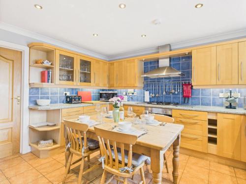 a kitchen with wooden cabinets and a table with chairs at Spacious 3-Bed Home in North Cornwall | Walk to Wadebridge | Near Camel Trail, Padstow & Rock | Free Parking in Wadebridge