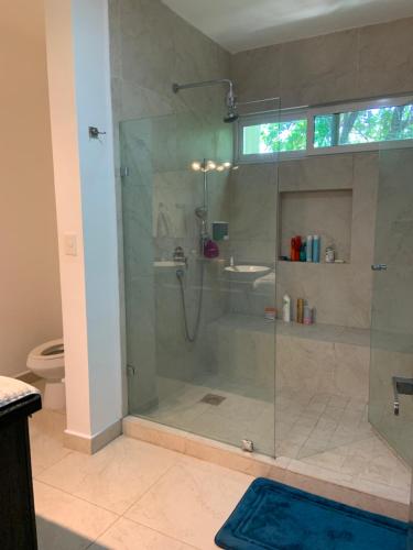 Un baño con ducha de cristal con lavabo. en La Escondida 34, en Playa del Carmen