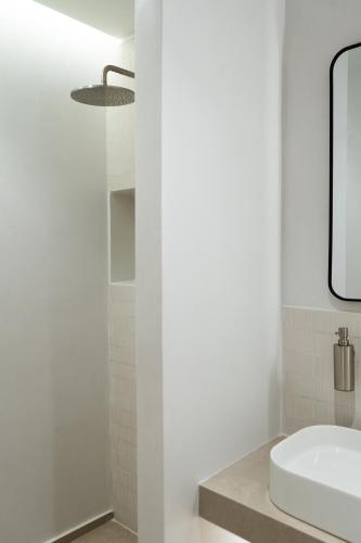 a white bathroom with a sink and a mirror at KYMA Suites Andros in Gavrion