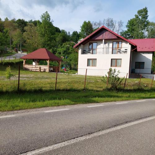 a white house with a red roof on the side of a road at Casa Valea Arefului in Arefu