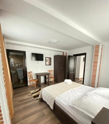 a bedroom with a bed and a table and chairs at Casa Corbeanu Transfagarasan in Bucşeneşti