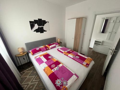 a bedroom with a bed with pink and purple sheets at Mića Apartment in Veliko Gradište