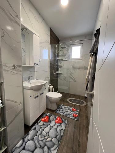 a bathroom with a toilet and a sink with rocks on the floor at Mića Apartment in Veliko Gradište