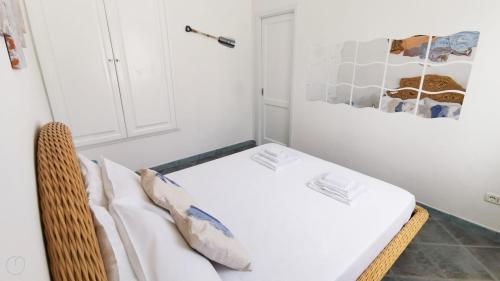 a room with a bed with white sheets and pillows at Villetta Il Faro sul Mare in Àrbatax