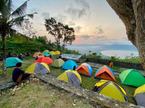 a group of people sitting in the grass with their tents at Enjoy Sunrise Pacitan Camping Ground in Tamperan