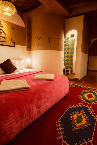 a bedroom with a large bed with a red blanket at Auberge La Fibule Du Dades in Aït Idaïr