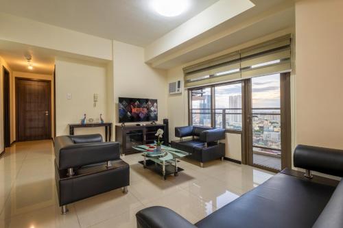 a living room with a couch and chairs and a tv at The Radiance Manila Bay in Manila