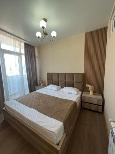 a bedroom with a large bed and a large window at Batumi Sea Apartment in Batumi