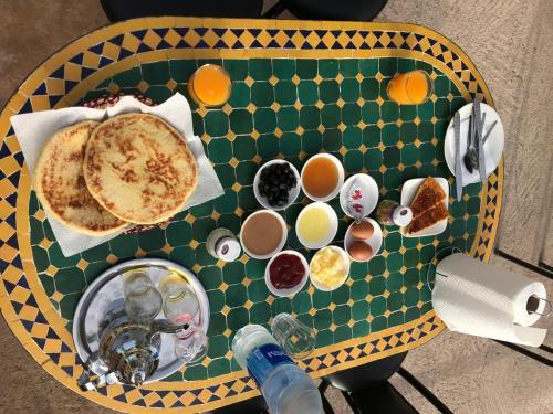 a table with a breakfast of pancakes and cups of coffee at Dar rachid ouzoud in Azilal