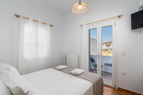 a white bedroom with a bed and a balcony at Aphrodite's Child Milos Maisonette in Adamantas