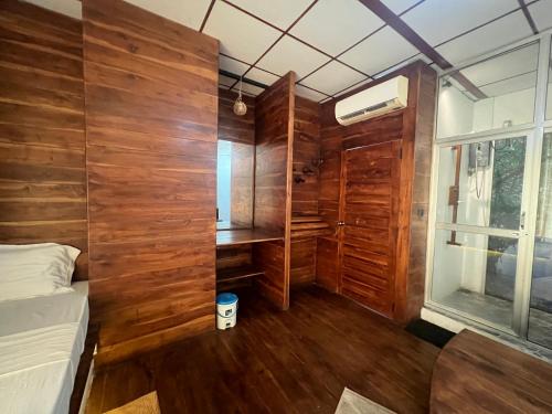 a bedroom with wooden walls and a bed and a desk at Wilpattu Nature Resort in Murandanveli