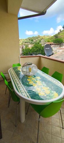a table with green chairs and a plate on it at Tra mare e collina in Condrò