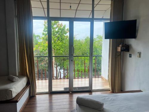a bedroom with a large glass door to a balcony at Wilpattu Nature Resort in Murandanveli