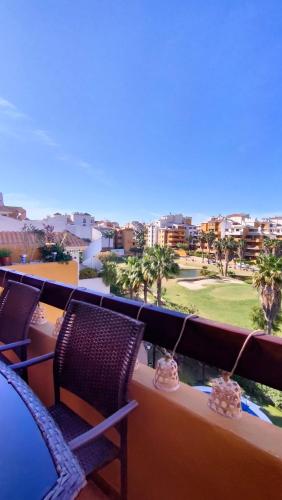 a balcony with chairs and a view of a golf course at Apartamento La casa Verde in Punta Prima