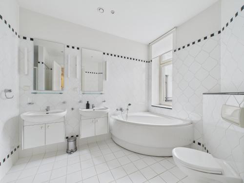 a white bathroom with a tub and a sink and a toilet at K1820 Family apartments in Rīga